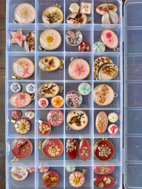 Contoh bandul resin dengan bunga berwarna pink, krem, dan merah dalam kotak