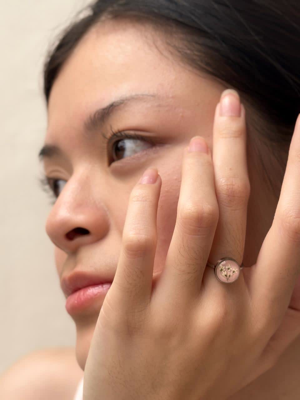 Cincin bunga berwarna pink dikenakan di jari