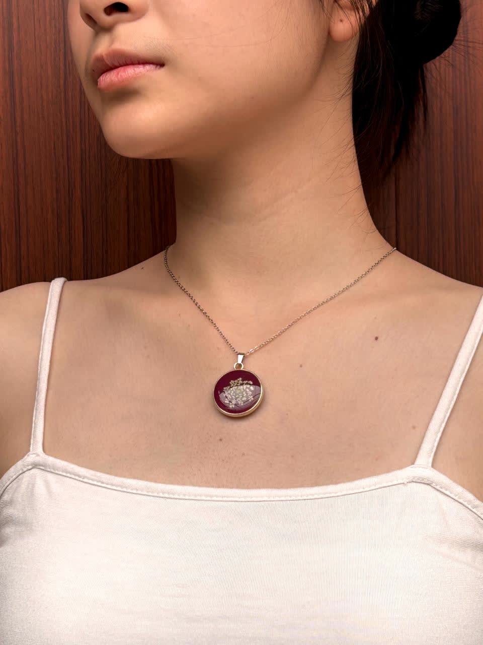 Kalung liontin bulat maroon dikenakan di leher