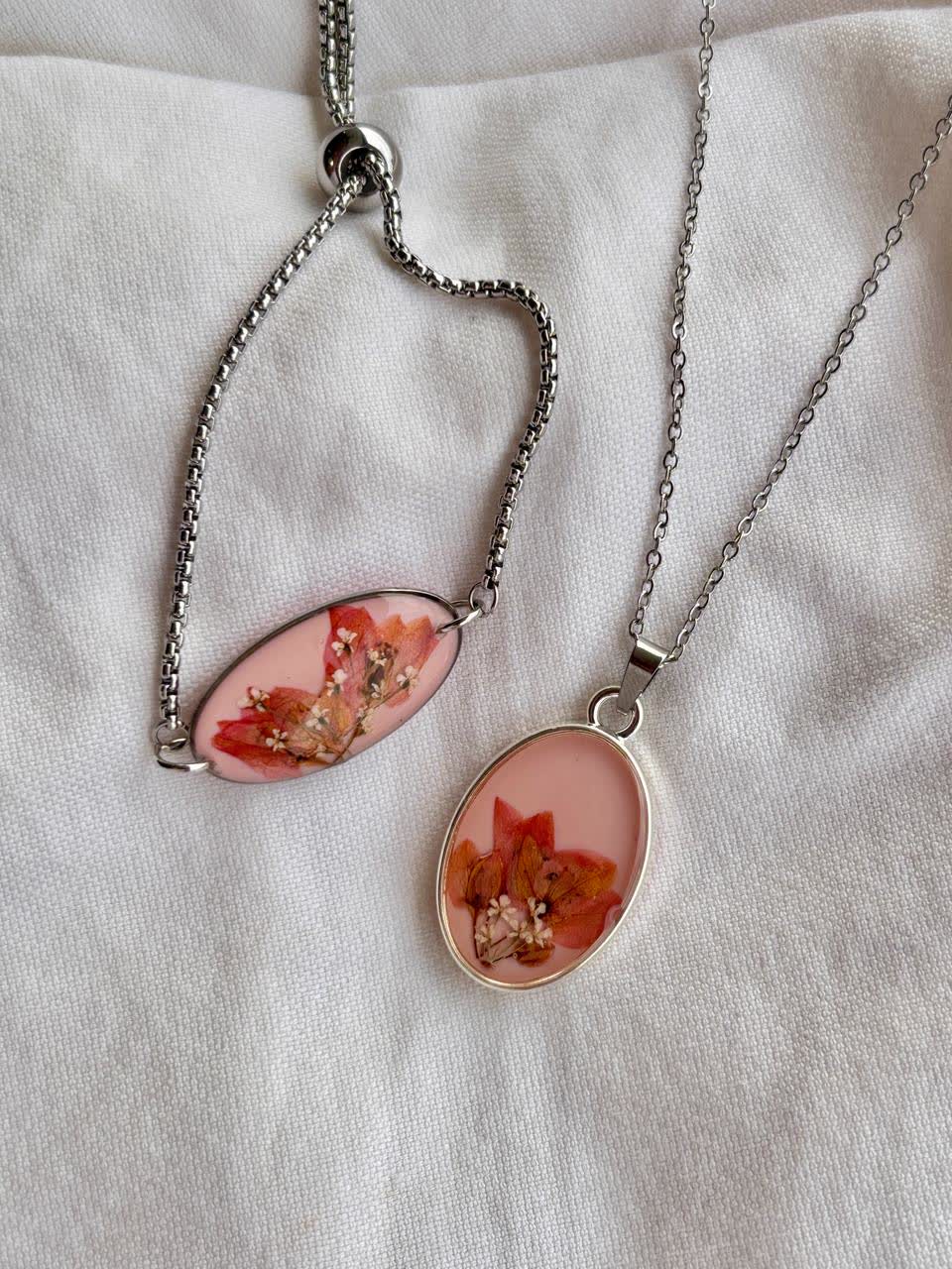 Gelang dan kalung resin bunga pink di atas kain putih